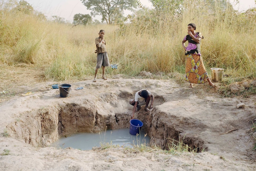 A farming family collects water from a hand-dug open well in Agaku, Nigeria.