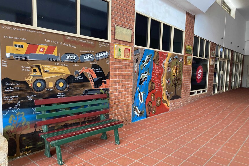 Murals painted on the walls of a municipal building showing mining operations and native animals.