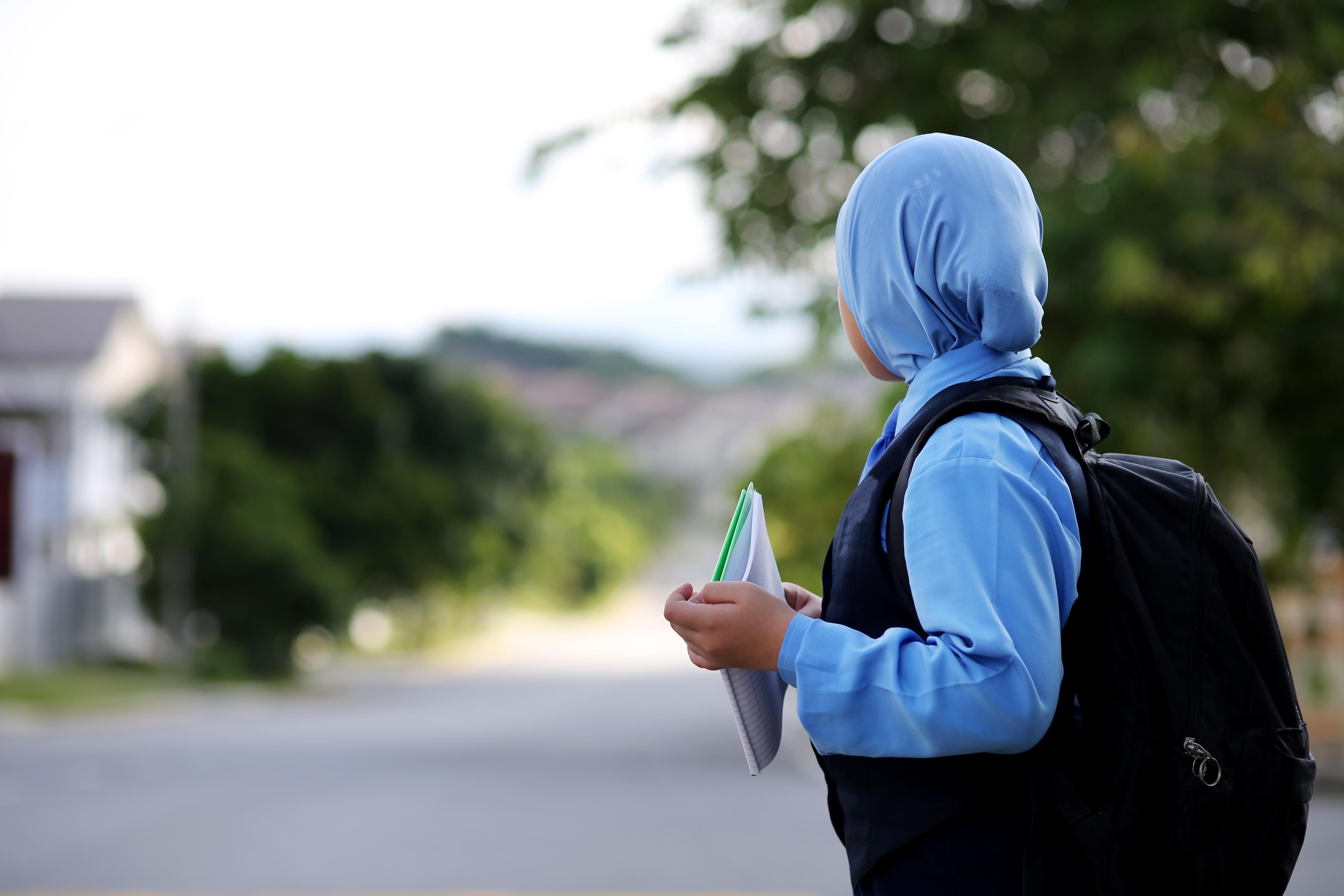 Muslim girl waiting for a bus to go to school