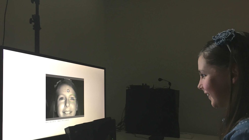 A young girl sits in front of an eye-tracking computer monitor.