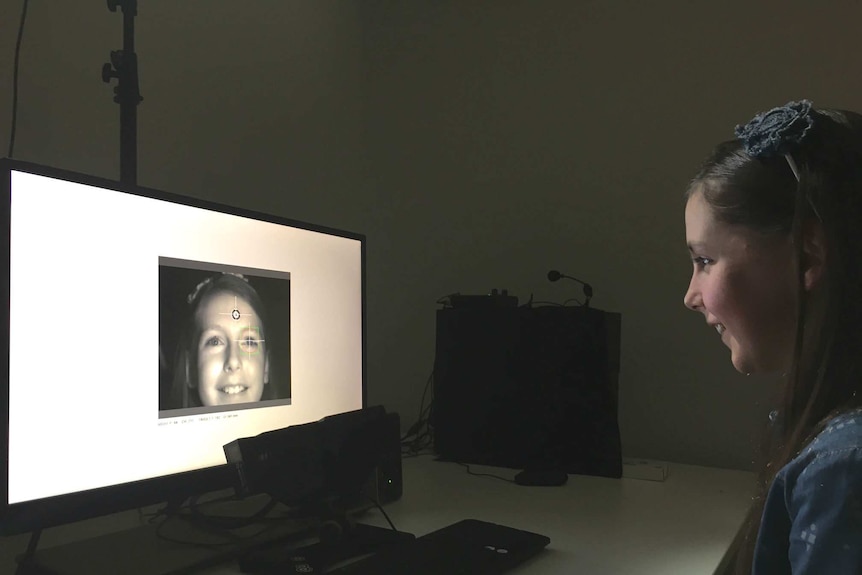 A young girl sits in front of an eye-tracking computer monitor.