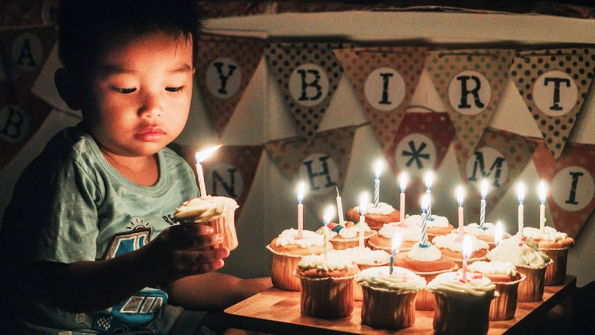 A young boy holds a birthday cupcake for a story on people pulling out of kids' parties