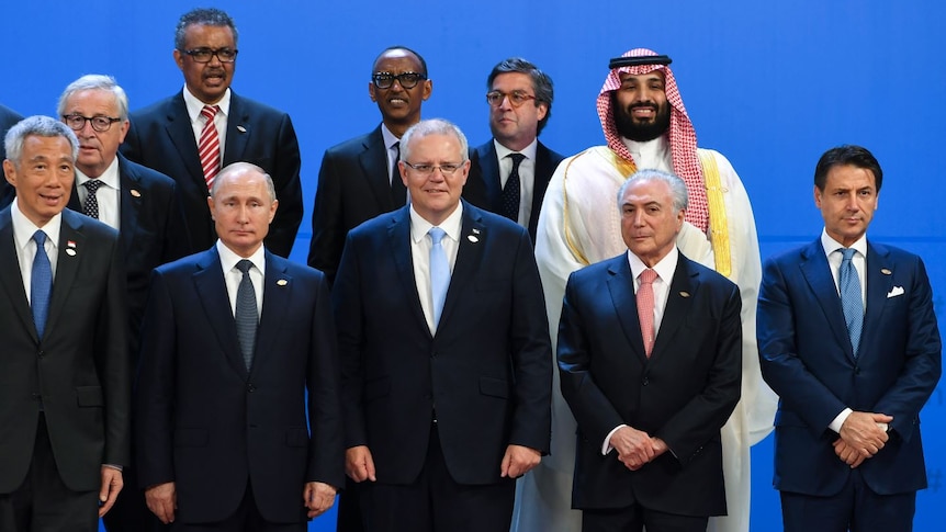 Scott Morrison stands among world leaders in front of a blue backdrop.