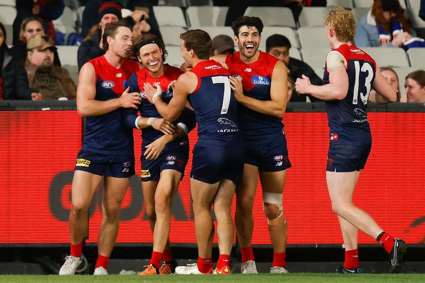 Christian Petracca et d'autres joueurs de Melbourne sourient en félicitant Ed Langdon