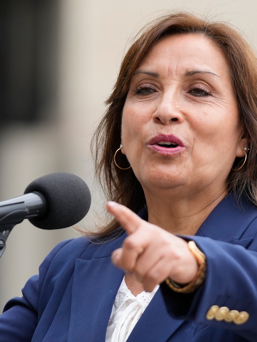 Peru's new President Dina Boluarte points as she makes a statement to the press.
