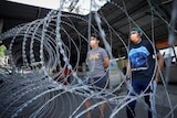 Residents wearing face masks stand behind barbwire in Malaysia