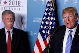 Donald Trump speaking at news conference at the G7 summit, standing next to John Bolton and Larry Kudlow.