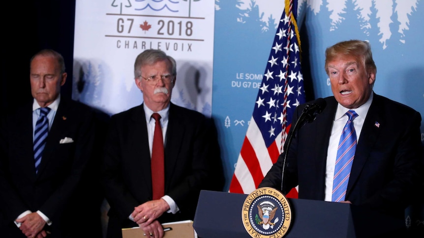 Donald Trump speaking at news conference at the G7 summit, standing next to John Bolton and Larry Kudlow.