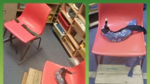 A red school chair with a weighted belt strap and foot box.