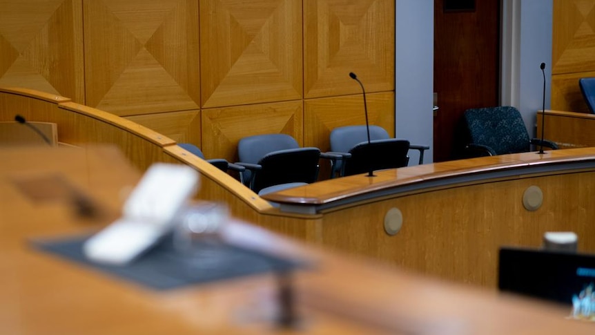 An out-of-focus judge's bench in the foreground and jury box in the background.