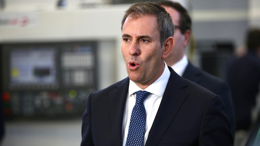 A man in a suit speaks at a press conference. 