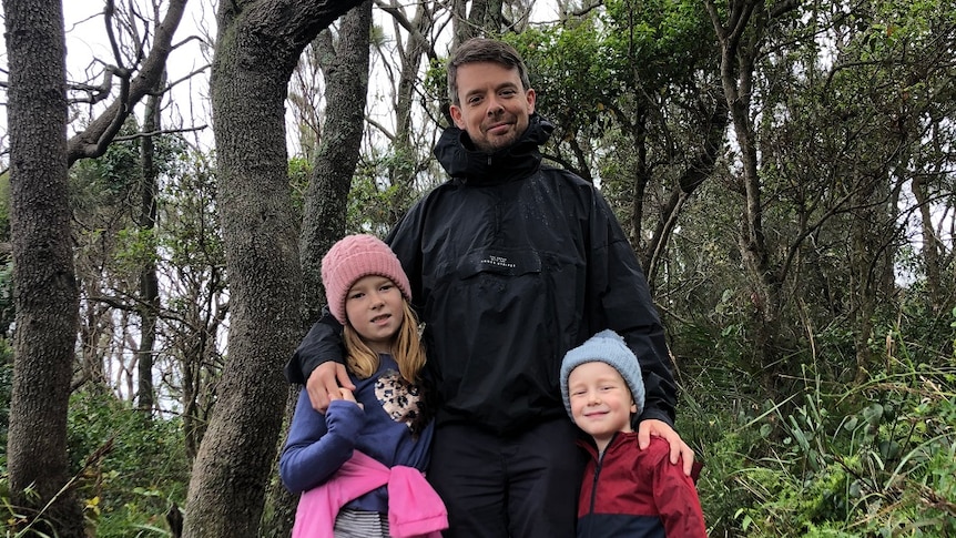 A man and his two kids in the forest