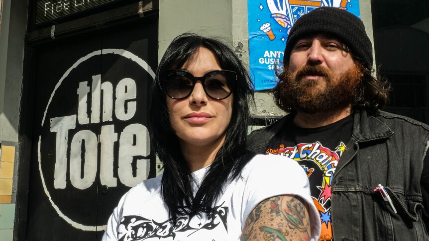 A woman in shades and man in beanie pose outside the front of Collingwood pub The Tote