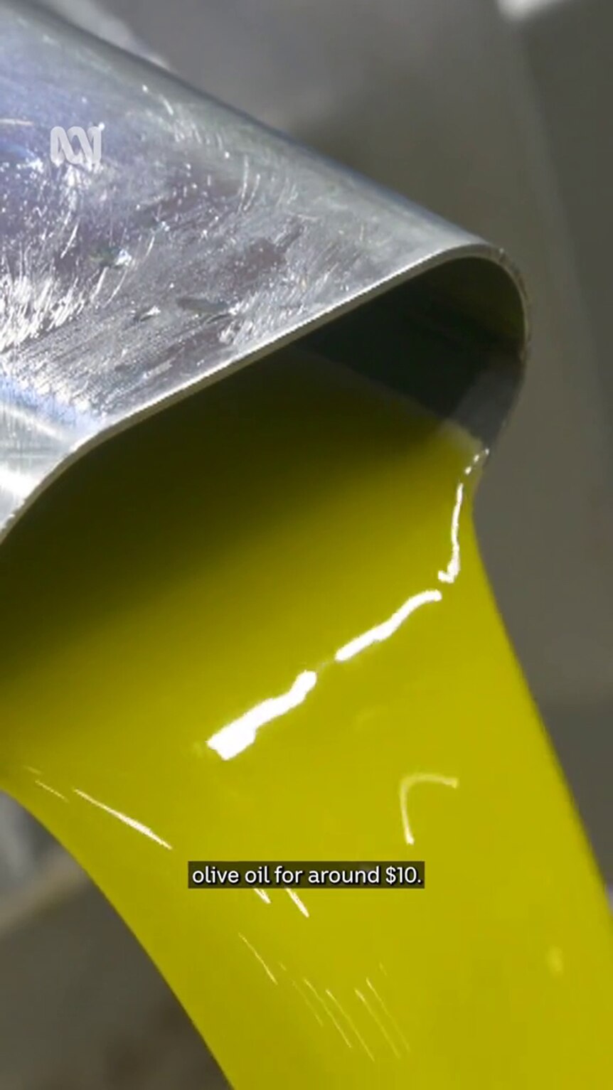 A yellow, shiny viscous substance streams from a clean flattened metal pipe