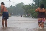 Two people stand in floodwaters on Rapid Creek Road