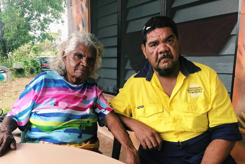 The pair sit outside a house