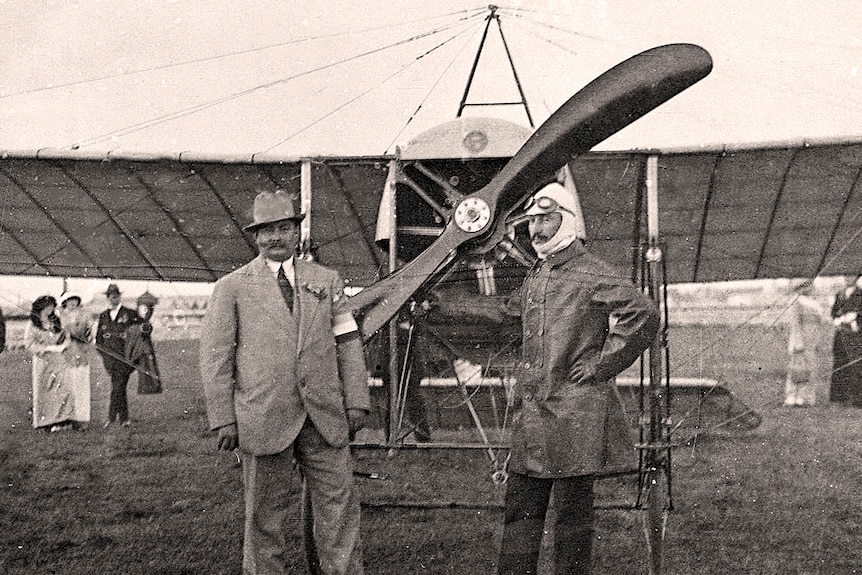 Four men stand in front of a gypsy moth biplane holding calico sacks with P.M.G Air Mail written on them.