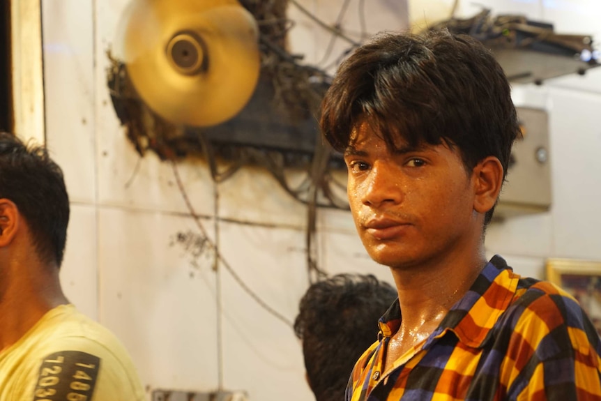 A young man is covered in sweat in a kitchen.