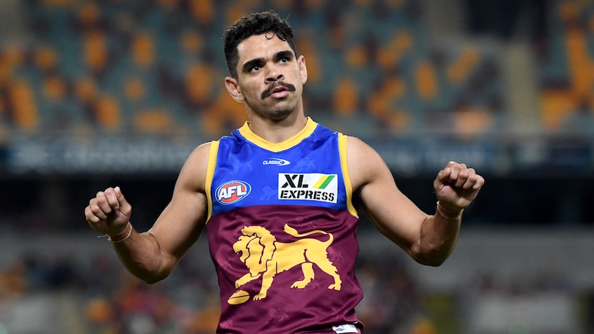 An AFL footballer revs an imaginary motorcyle in celebration after a goal.