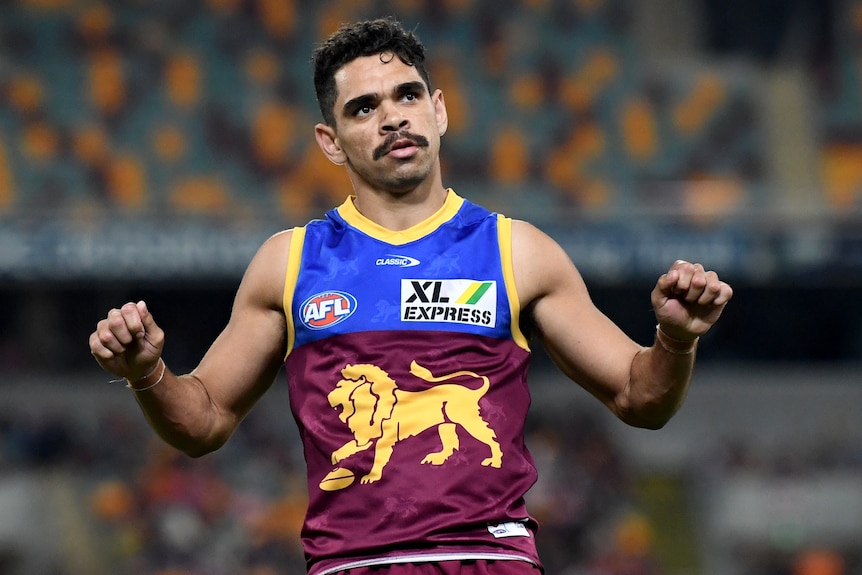 An AFL footballer revs an imaginary motorcyle in celebration after a goal.