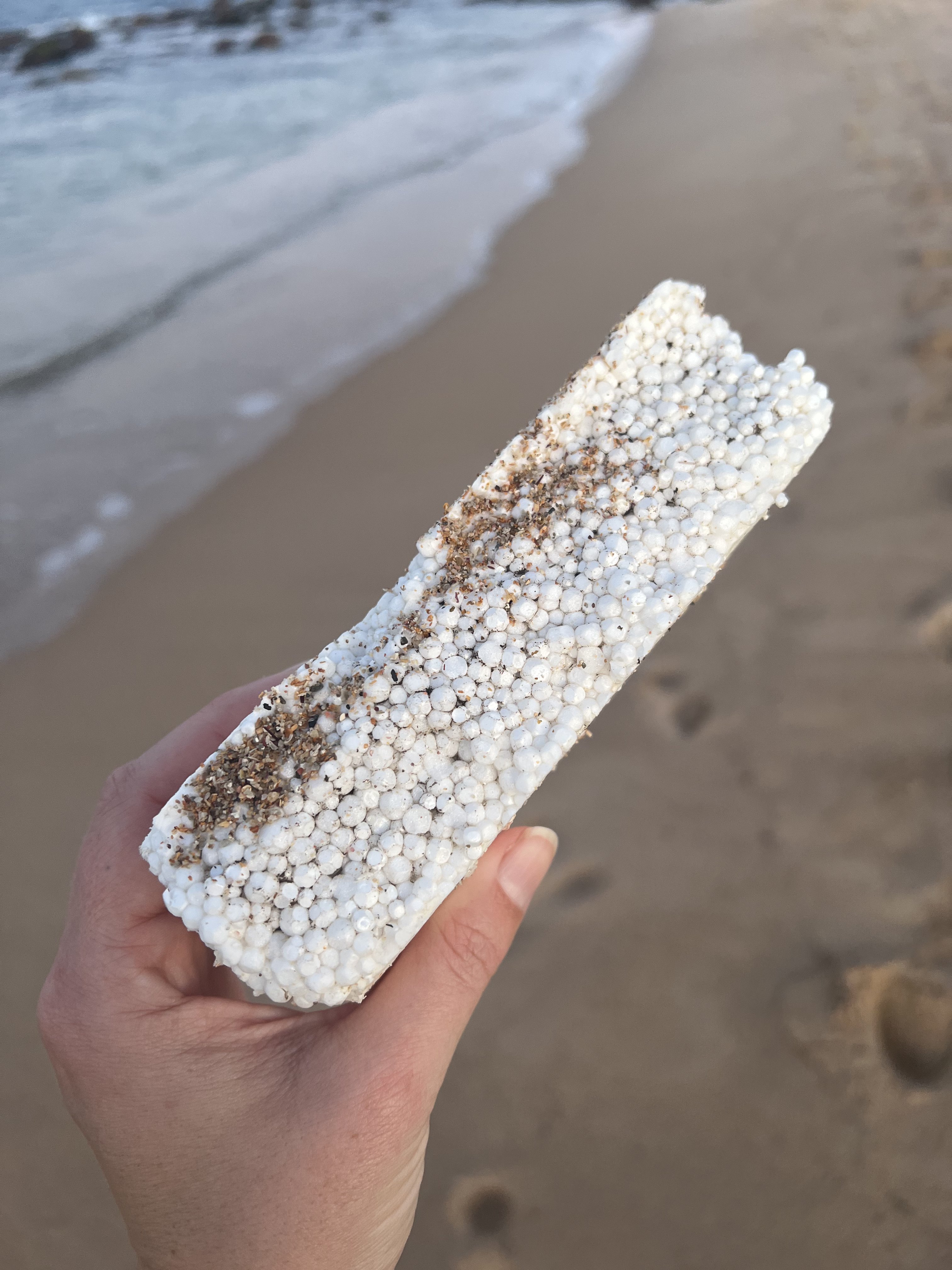 Un poste con pequeñas bolas de plástico sostenidas en una mano en la playa.