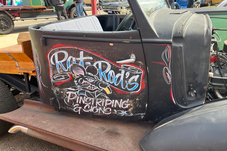 The door of a car has the words rat rod painted on it.