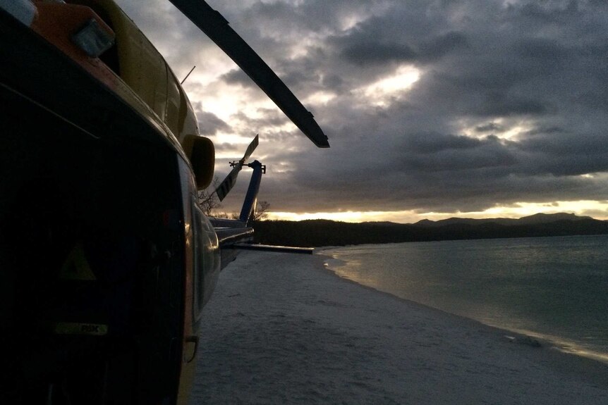 RACQ CQ Rescue helicopter waits on Whitehaven Beach as sun sets