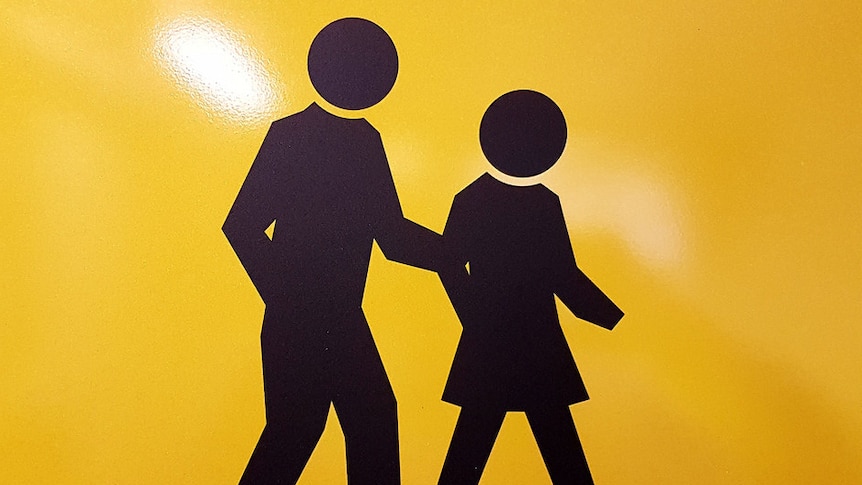 A yellow and black sign indicating a pedestrian crossing.