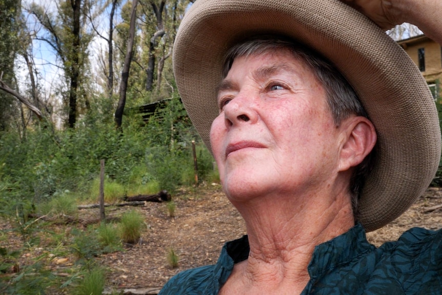 Close up of woman on burnt property looking up thoughtfully