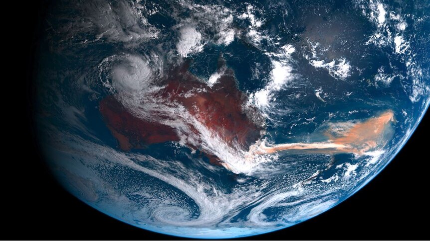 A satellite view of the Australian continent and a reddish plume flowing over the ocean from the east coast