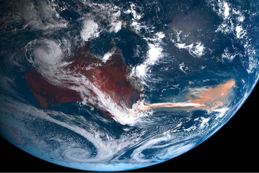 A satellite view of the Australian continent and a reddish plume flowing over the ocean from the east coast