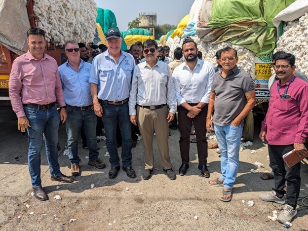 Un grupo de hombres australianos e indios frente a un campo de algodón.