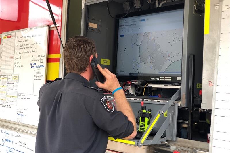 A fire officer looks at a digital map in the side of a truck whilst on the phone.