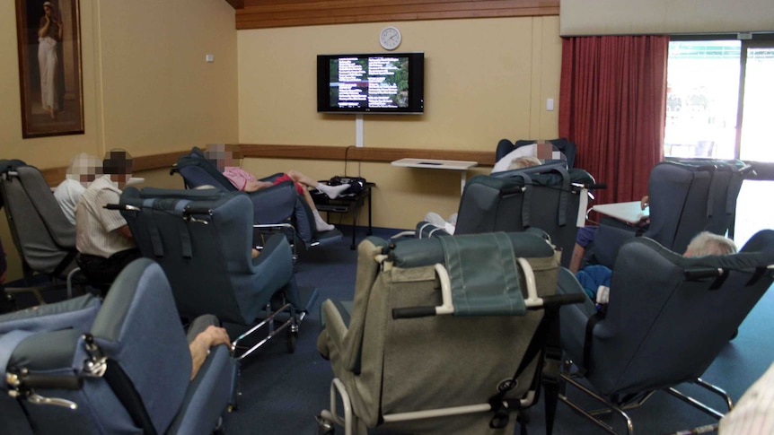 Nursing home residents in chairs around a television.