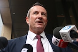 A close-up shot of WA Premier Mark McGowan speaking with microphones below his chin.