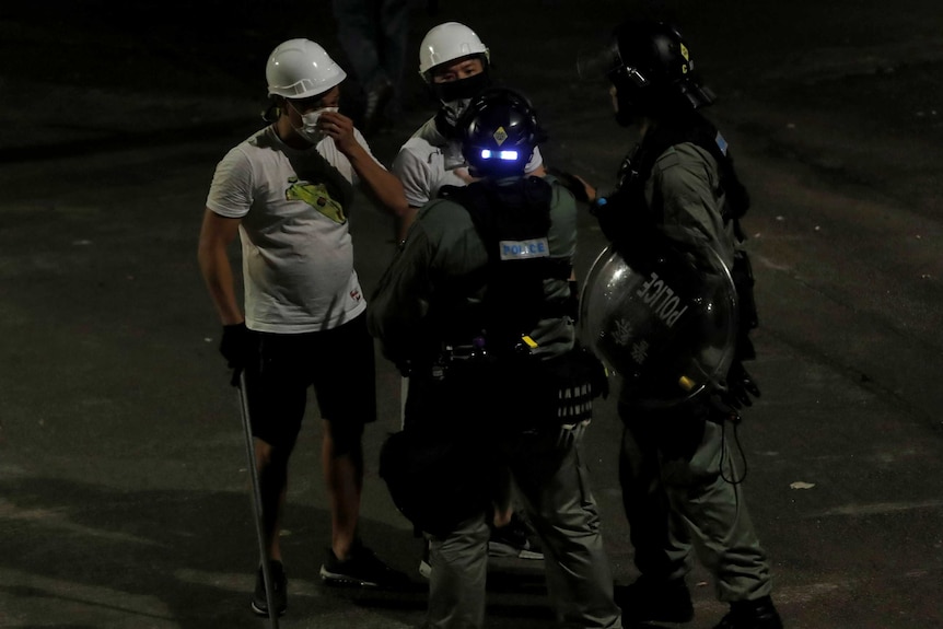 在反引渡条例抗议者遇袭之后，身穿白色衣服的男子在元朗与防暴警察交谈。