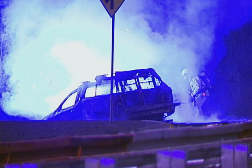 Firefighters work to douse a car ablaze after a high-speed chase near Brisbane