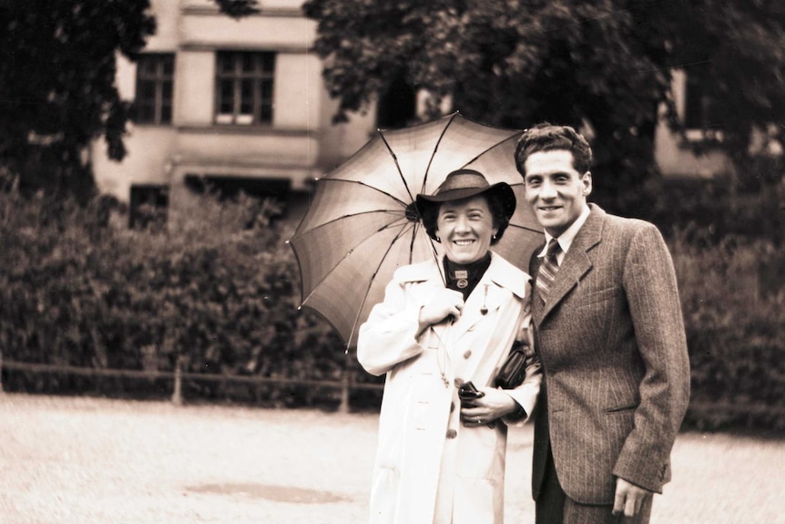 Black and white photo of a woman and man outside, woman holding umbrella.