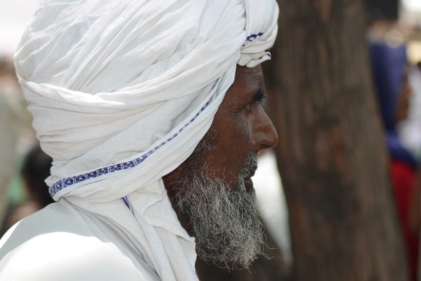 A closeup, side-view of a Muslim man in India.
