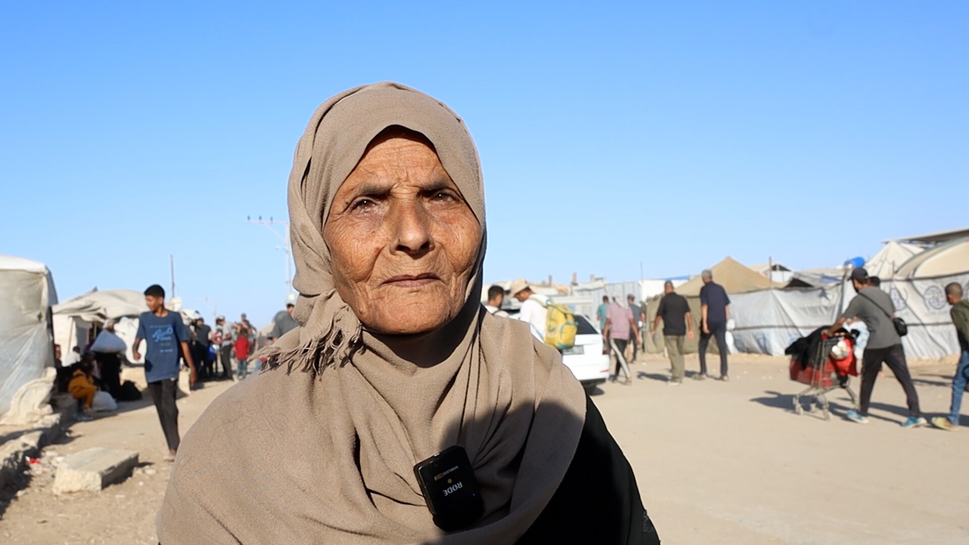 An older woman wearing a hijab standing in a road