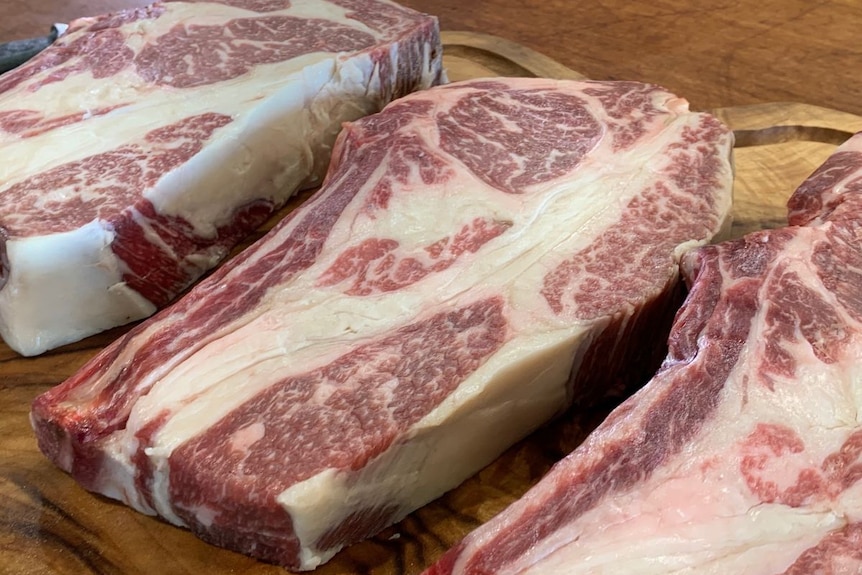 Marbled steaks laid out on a board.