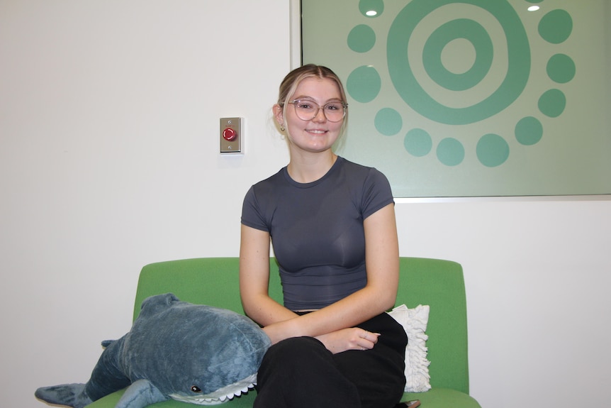 A young woman sits on green couch