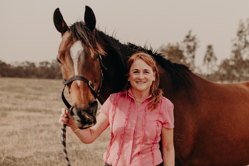 Lady smiles while holding horse