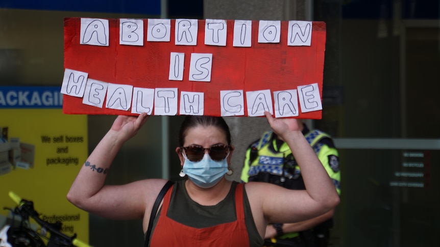 A woman holds up a saying saying 'Abortion is health care'