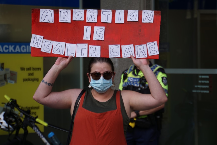 A woman holds up a saying saying 'Abortion is health care'