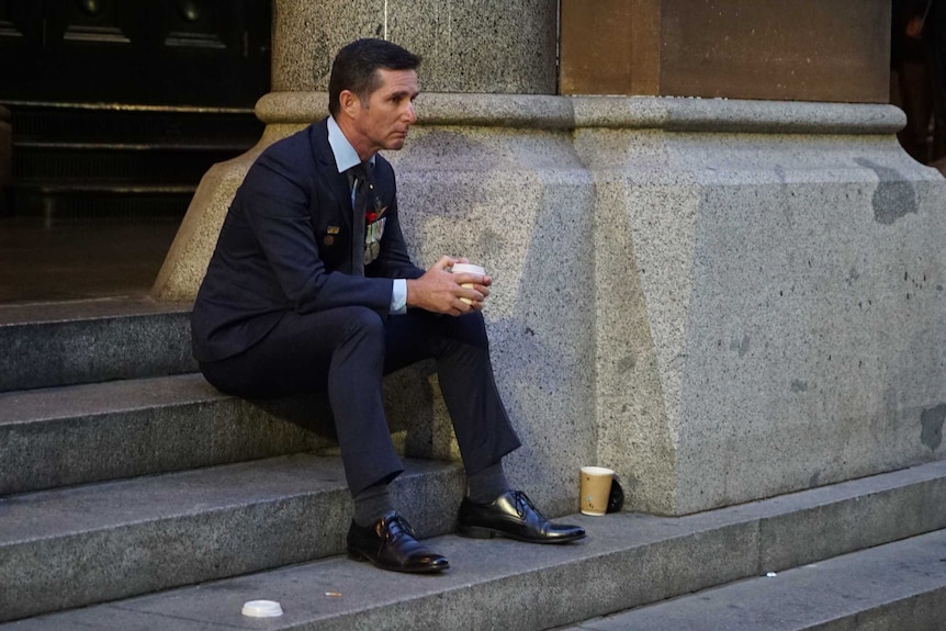 A man sits alone on a step in Martin Place