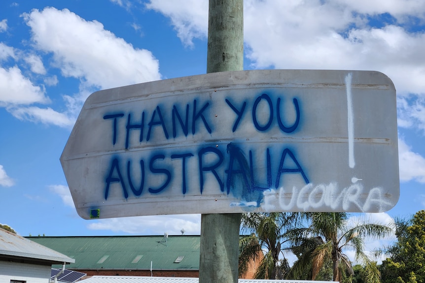 The back of a street sign in Eugowra with spray paint on it saying 'Thank you Australia'