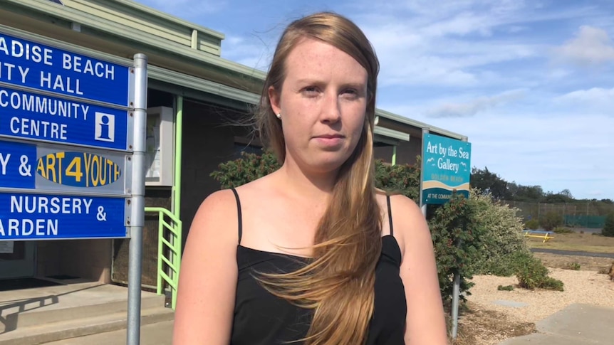 A young woman stands in front of signs at Ninety Mile Beach in eastern Victoria