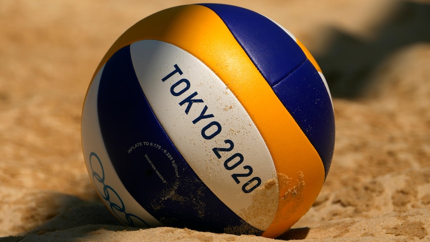 A close-up photo of a volleyball with "Tokyo 2020" in the sand. 