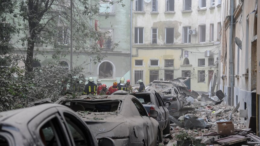 a street with destroyed parked cars and shattered building next to them